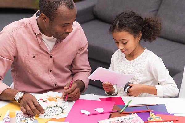 A father and daughter making greetings cards from paper.