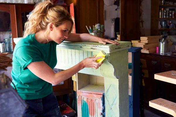 A woman painting an upcycled mantle piece.